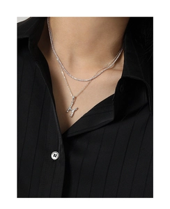 Detail of layered S925 sterling silver necklace with irregular lava-textured letter H pendant