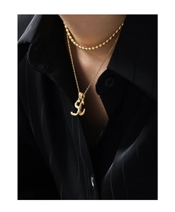 Detail of layered gold S925 silver necklaces with alphabet pendant and bead chain