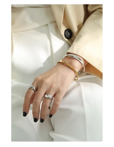 Detail of twisted silver and gold bangles paired with polished minimalist rings