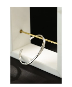 Macro shot of silver twisted open bangle with polished finish on gold display rod