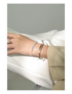 Detailed close-up of a S925 sterling silver minimalist cuff and feather charm bracelet