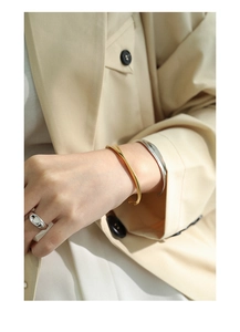 Polished silver and gold minimalist open bangles paired with wide band ring on wrist