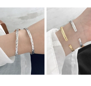 Detail showing irregular foil texture on C-shaped open silver and gold bracelets