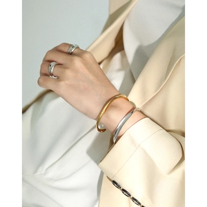 Minimalist silver and gold open bracelets with chunky polished rings on a model