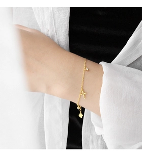 Dettaglio del bracciale in argento S925 dorato con croce, ciondoli a cuore e zirconi
