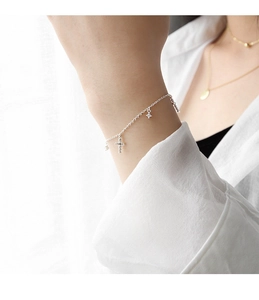 Dettaglio del bracciale in argento S925 con ciondoli a croce sul polso della modella