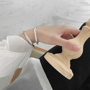 Irregular textured silver bangles with handmade fold design shown on model and wooden stand