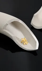 Macro shot of matte gold clover petals S925 silver clip earrings on a stone prop