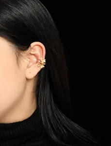 Detailed view of golden double leaf ear cuff with vein texture on woman's ear
