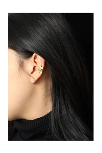 Close-up of golden clover ear cuff with textured finish on model ear without piercing