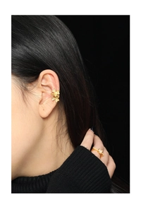 Detailed view of matte gold clover ear cuff with three stacked flowers and hammer texture