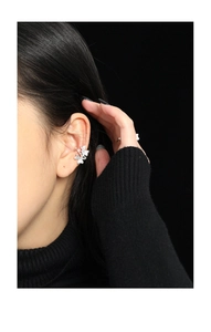 Macro shot of silver clover ear cuff with micro-paved zircons on a dark aesthetic background