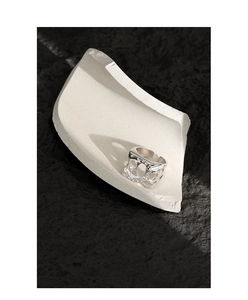 Macro detail of silver hollow irregular ring on minimalist ceramic and black background