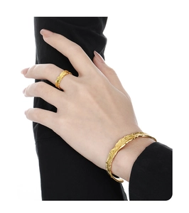 Primo piano dell'anello dorato e del bracciale aperto con texture lava irregolare