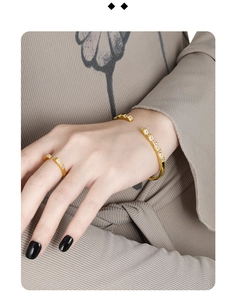 Detail of geometric gold cuff and ring set featuring rectangular clear stones on model