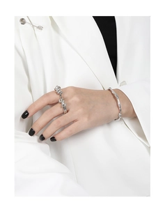 Close-up of a silver twisted knot ring and bracelet set on a model in a white blazer