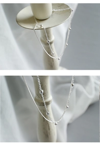 Détail de la chaîne de cheville double couche en argent S925 avec perles sur socle blanc