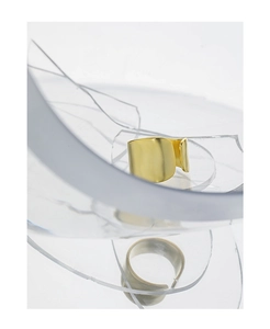 Detailed view of wide matte gold open ring set against artistic crushed glass
