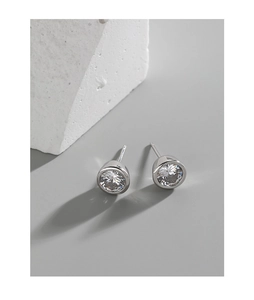 Macro shot of silver S925 round cubic zirconia stud earrings on geometric stone pedestals