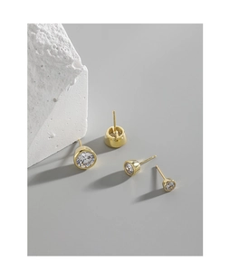 Detailed view of two pairs of gold S925 silver stud earrings with round cubic zirconia