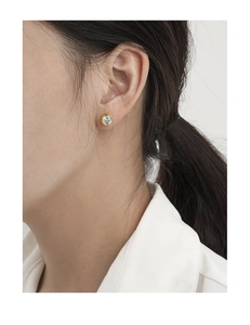 Detail of minimalist S925 silver stud earring with round zircon and gold bezel on ear