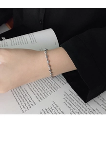 Nahaufnahme eines minimalistischen S925 Silberkettenarmbands am Handgelenk über einem Anzug