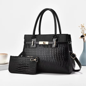 Detail of black crocodile texture lacquer handbag set with golden metal twist lock and strap
