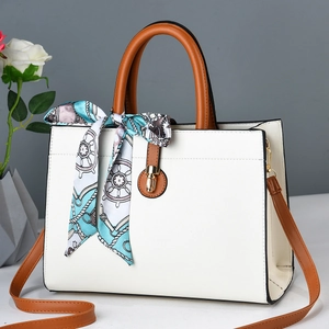 Detail of elegant beige tote bag with brown contrast trim and silk scarf accent