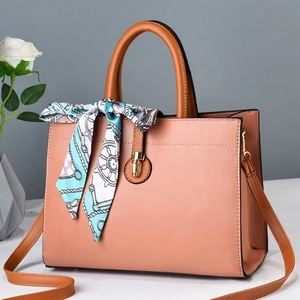 Detail of salmon pink faux leather tote bag with silk scarf and gold twist-lock buckle