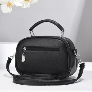 Minimalist black pebble leather mini crossbody bag with silver hardware and top handle