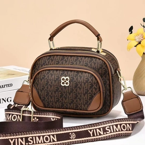 Dettaglio di una borsa rotonda marrone monogram con doppia zip e tracolla larga