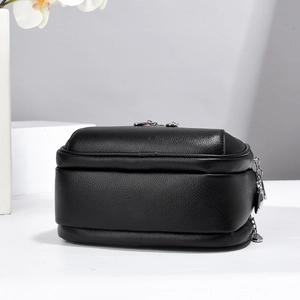 Detail of black pebbled leather mini round handbag with silver zipper and texture