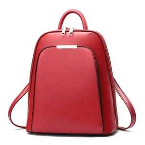 Front view of large red synthetic leather backpack with front zipper pocket and top handle
