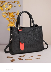 Detail of black crocodile texture handbag with orange tassel and golden buckle