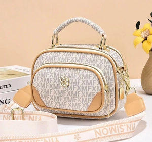 Dettaglio della borsa a tracolla beige con stampa lettere MFX e logo in metallo dorato