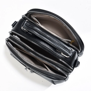 Top view of black multi-compartment crossbody bag showing four zippered interior sections