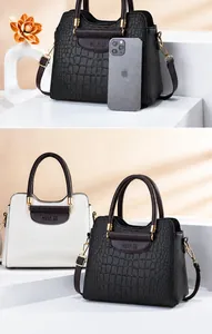 Detail der Handtasche mit Krokodilprägung, Goldbeschlägen und Größenvergleich im Detail