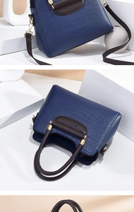 Detail der dunkelblauen Handtasche mit Krokoprägung, braunen Griffen und Goldbeschlägen