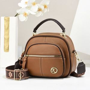 Brown lychee leather crossbody bag with wide woven strap and gold hardware details