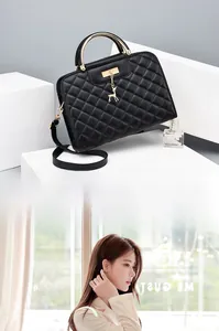 Detail of black quilted crossbody bag with golden deer charm and circular metal handle