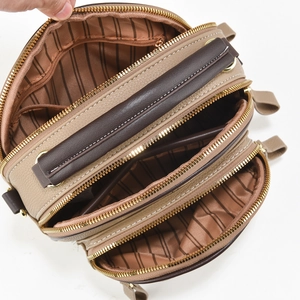 Top view of multi-layer women bag with three gold zippers and striped lining detail