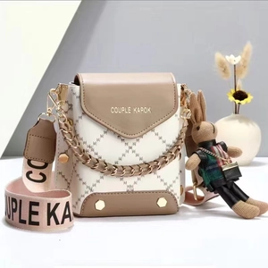 Detailed view of white quilted crossbody bag with golden chain and cute rabbit charm