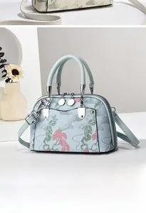 Detail der hellblauen Handtasche mit eleganten floralen Stickereien und doppelten Griffen