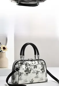 Detailansicht der beigen Muschel-Handtasche mit grauen Kiefernnadeln und Blumenmuster