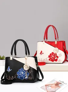 Detail der chinesischen Pfingstrosenstickerei und des Metalllogos auf der Handtasche