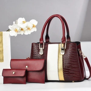 Detail of three-piece burgundy crocodile texture tote bag with matching clutches