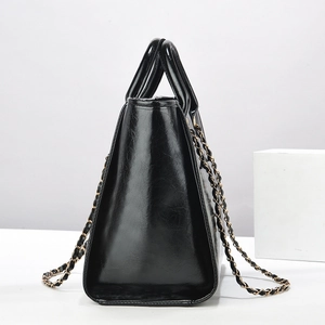 Classic black leather tote bag with glossy finish and chain shoulder strap at 45 degree angle