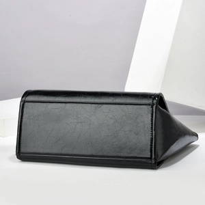 Detail of black faux leather handbag showing glossy crackle texture and wide base
