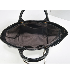 Macro view of black patent leather handbag interior showing brown lining and compartments