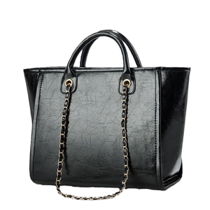 Large black shiny leather tote bag with elegant gold chain for professional women